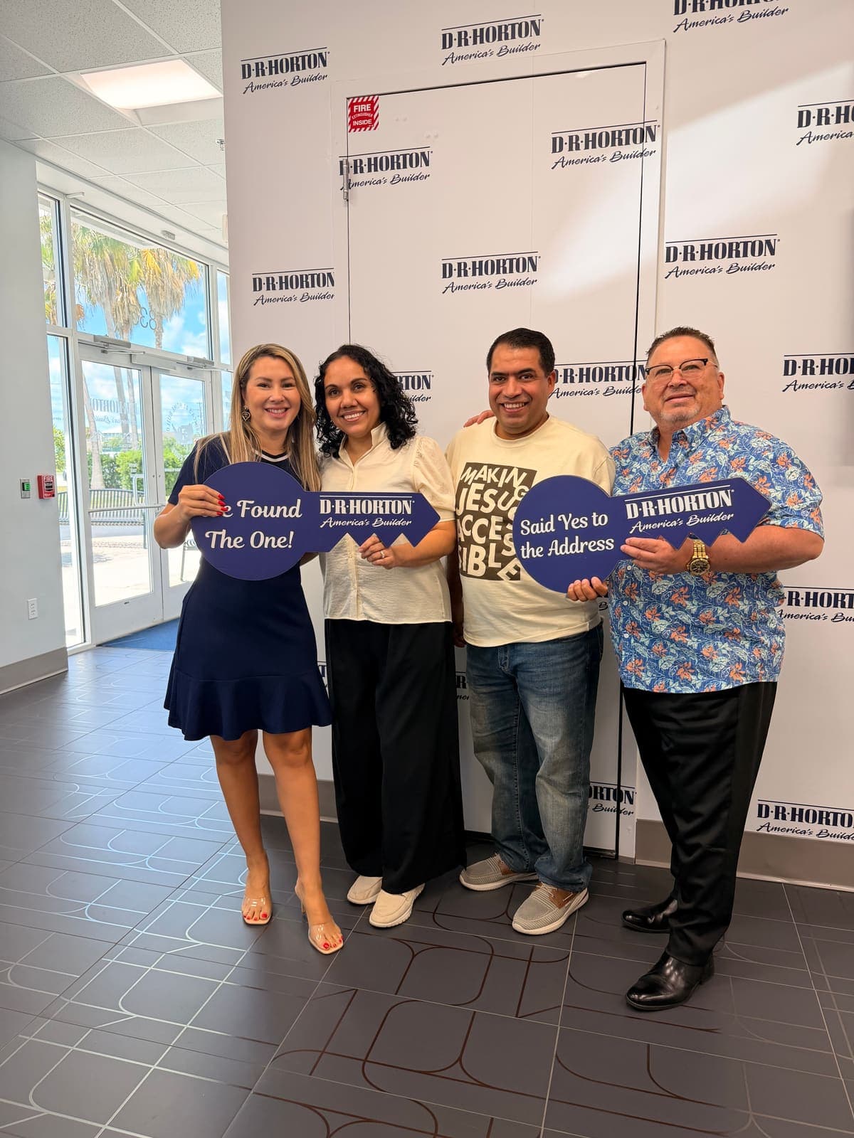 Buyers holding an oversized key at their new construction handover