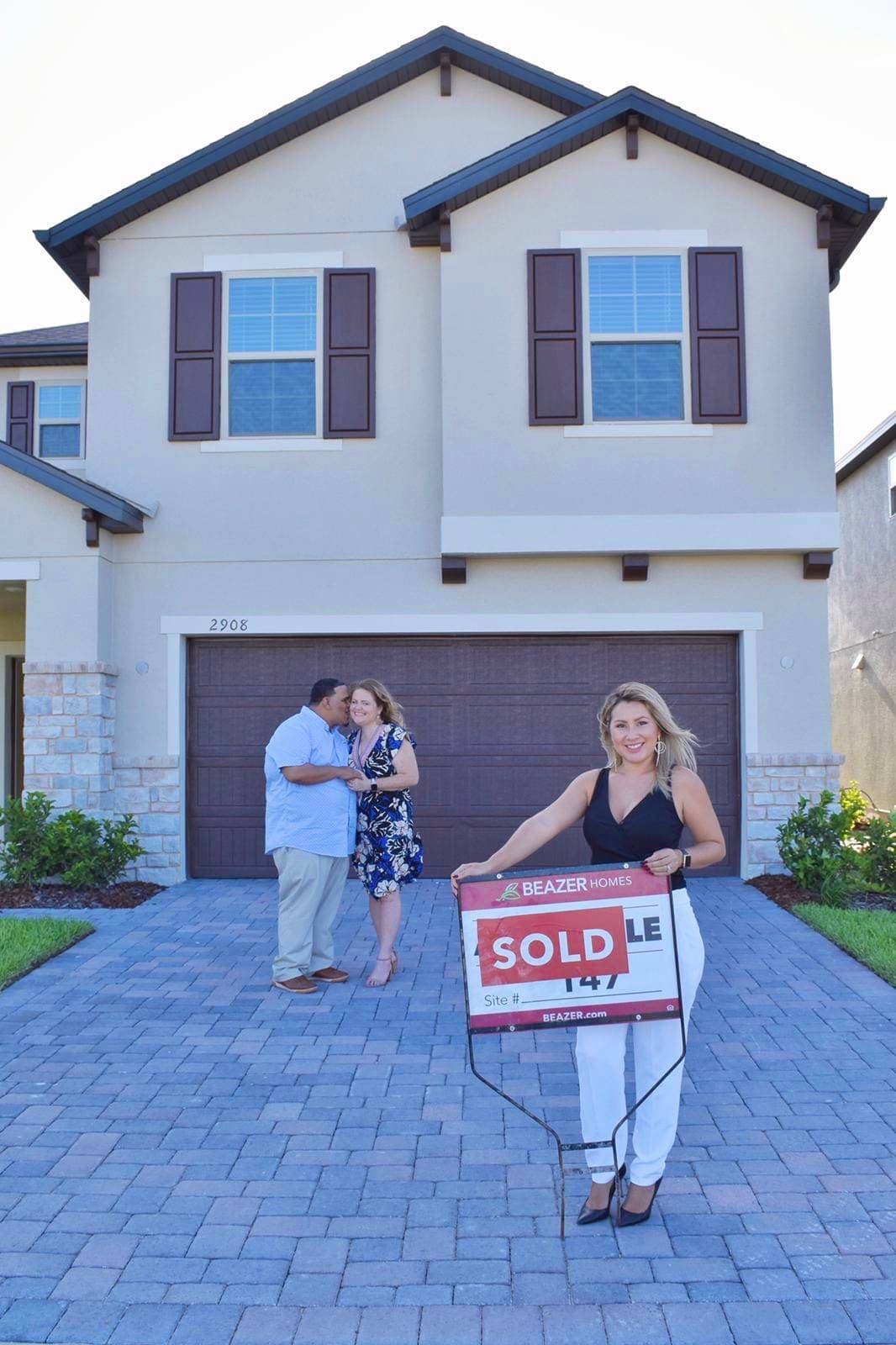 Buyers standing in front of their new Central Florida home beside the sold sign