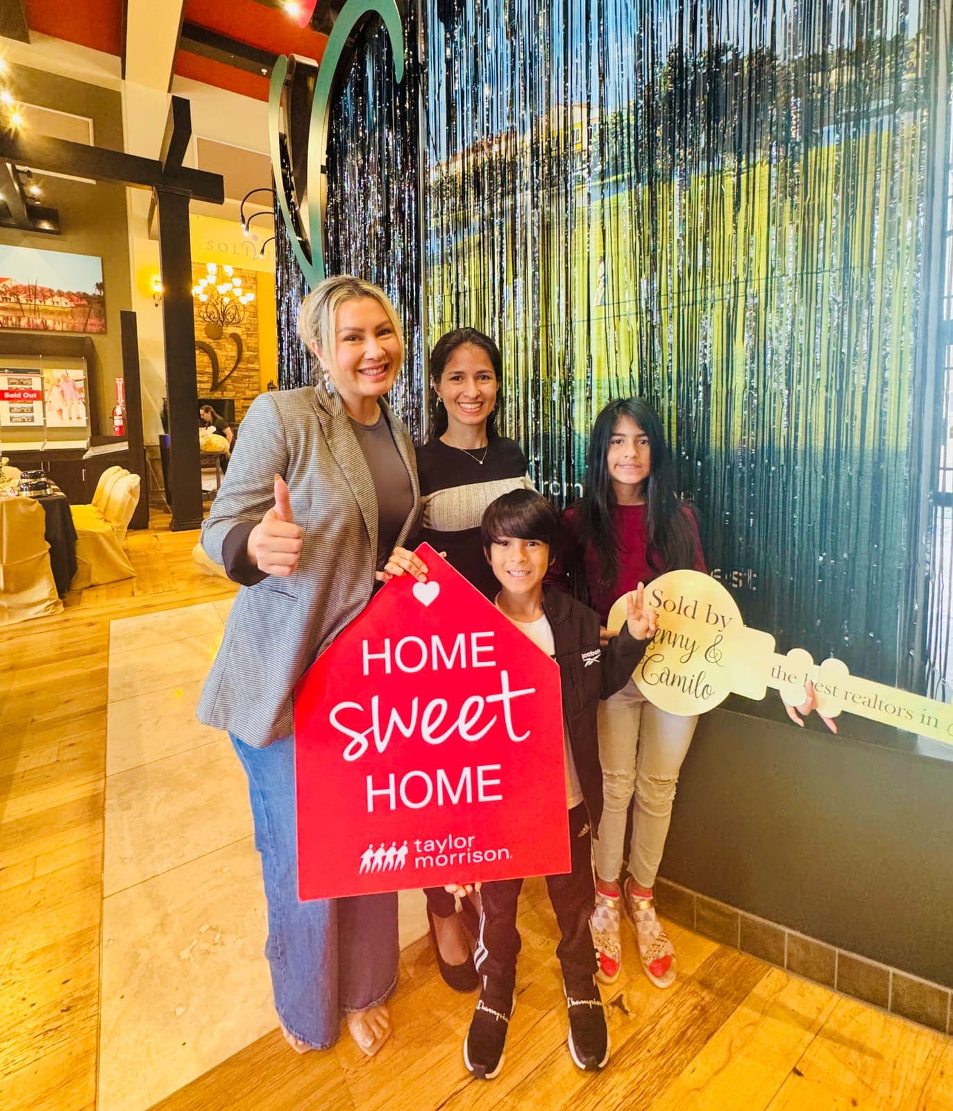 Buyers holding a Home Sweet Home sign after closing with Jenny Caso
