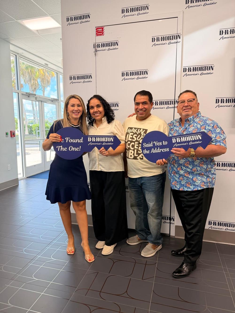 Buyers holding an oversized key at their new construction handover