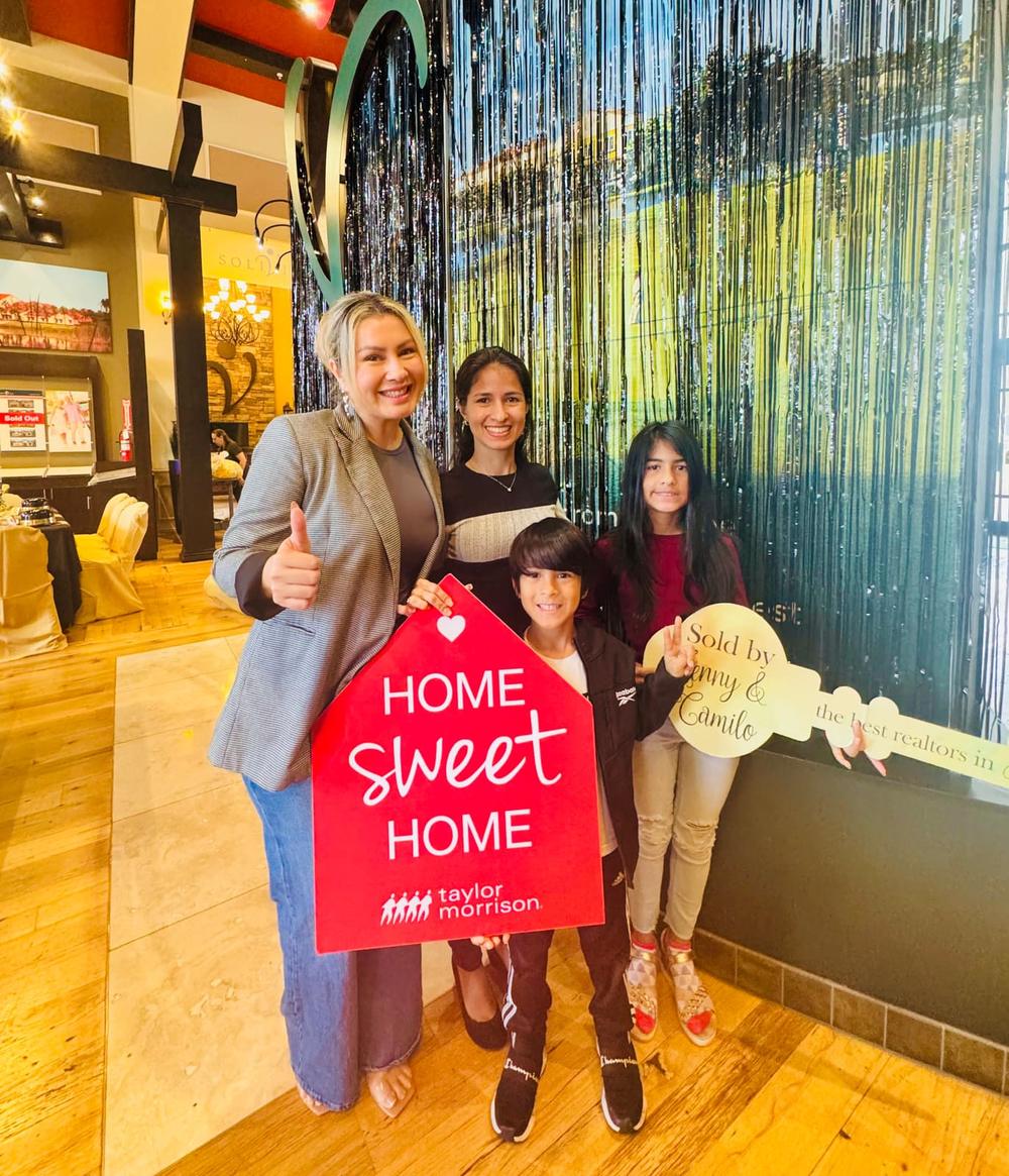 Buyers holding a Home Sweet Home sign after closing with Jenny Caso